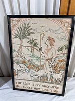 Framed cross-stitch artwork showing a shepherd with sheep and the text at the bottom.