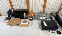 Wide view of the collected electronic devices including radios, speakers, projector, and boombox.