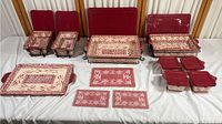 Full set of cranberry red trays and plates displayed on white cloth, showing variety of sizes and metal racks.