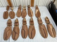 Top-down view of six hardwood shoe keepers molds arranged on table showing natural wood grain and split toe design with brass hinges.