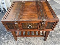 Top-front angled view showing the ornate embossed panels on drawer and sides, wood grain finish, and metal stud details.