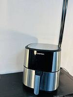 Front view of Chefman TurboFry Touch XL 8-Quart Air Fryer on black surface against white background, showing stainless steel and black housing and front handle.