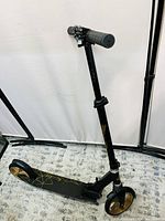 Side angle view of entire scooter showing frame, deck, front and rear wheels, and handlebars adjusted to a lower height.