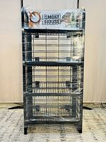 Front view of the black metal kitchen cart showing five wire shelves, wrapped in plastic, with a 'Smoke House' sign on top.