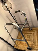 Photo of lightweight aluminum 2 wheel walker with padded hand grips and foldable hinge.