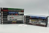 Front and back view of the game stack showing 14 games in original PS2 cases with titles readable on spines and covers.