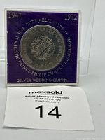 Clear photo showing the front of the commemorative silver coin in a purple display case, with text referencing Queen Elizabeth II and Prince Philip, 25th wedding anniversary 1947-1972.