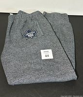 Folded grey Roots track pants showing Toronto Maple Leafs embroidery patch and macroid size 44 tag