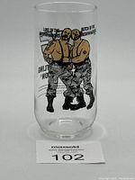 Clear glass featuring colored print of wrestlers Luke and Butch of The Bushwhackers facing each other.