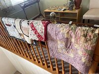 Four quilts draped over stair railing showing variety of colors and patterns