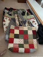 Overview of multiple handmade cloth bags stacked showing patchwork and floral fabric