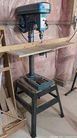 Full view of drill press on stand, showing head, column, table, and base.
