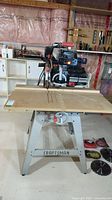 Front view of Craftsman radial arm saw mounted on metal base, blades on floor