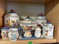 Full display of Villa Flora ceramic hand painted dish collection including covered containers, creamer, pedestal bowl, and tray