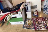 Box with various folded fabrics, quilting books laid in front titled 'Scrap Quilts' and 'Quilt Blocks & Borders'