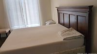 Full assembled view of king size bed with mattress and box spring against wood headboard