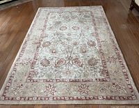 Unrolled view of 5'x8' area rug showing floral design and border pattern on hardwood floor.