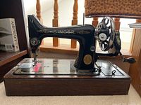 Side view of vintage black Singer sewing machine with gold decals on a wooden base.