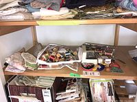 Shelf with sewing supplies showing a clear pouch with threads, fabric pouches, and metal sewing tools including cording foot