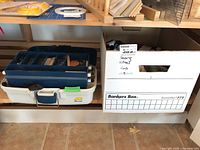 Photo showing a white toolbox with compartments and a white plastic container labeled 'Sewing Notions' containing various sewing supplies.