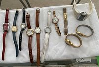 Overview of 9 ladies wristwatches on white cloth showing various styles and brands