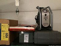 Overview of air compressor on top of toolbox, wood carving tool set in box, large cardboard box, and metal generator panel