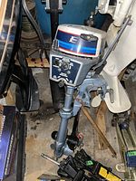 View of motor showing engine cover, throttle handle and clamp mount in garage