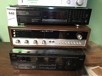 Four stacked audio components: Magnum Q800 IC receiver in wood finish, JVC RX-6010V receiver, Kenwood DP-4020 CD player, and Sanyo JT20 radio tuner