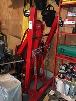 Front view of folded red engine leveler hoist showing frame, lifting chain and hook