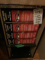 Four boxes of night vision glasses stacked inside a small black shelving cabinet.