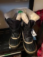 Front view of pair of black winter boots with faux fur lining and laces, new with tags attached