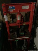 Full front view of red steel shop press with hydraulic jack and press blocks installed