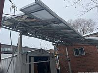 Underside view of sixteen solar panels mounted on metal rack above ground showing wiring and mounting frame