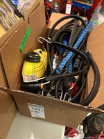 Box containing multiple tie down straps including yellow ratchet strap and assorted bungee cords.