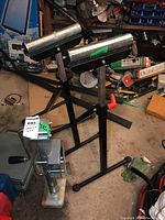 Shows the two roller stands with black tripod bases and cylindrical rollers.