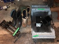 Overview of all items: woodworking vise, two metal creepers, black rubber boots, tan and black work boots showing condition and scale.