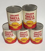 Front view of 5 Golden Shell Motor Oil display cans stacked in two rows showing the classic red and yellow branding with Shell logos.