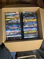 Photo showing a box with two stacks of various DVD cases arranged side by side.