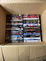 Top-down photo of a cardboard box filled with DVDs arranged with titles visible on spines