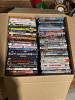 Box opened showing DVDs stacked in rows revealing titles and variety of movies.