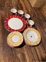 Overall view of the china set including plates, bowls, and coffee mugs arranged on wooden floor.