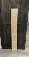 Full view of the wooden height ruler showing measurement markings and numbers from 2 to 6 feet