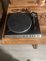 Full view of the Toshiba SR-F102 belt-drive fully automatic turntable on wooden surface showing the platter, tonearm, and control buttons.