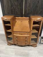 Solid wood secretary desk with two side glass cabinet doors, shelves, drop-down writing surface closed, and three bottom drawers.