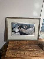 Full view of the framed print depicting seals on rocks by the water.