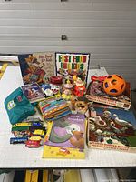 Full lot on table showing books, toys, puzzles including a toy train set, clown figurine, shape sorter ball and various children's books.