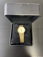 View of gold colored Pierre quartz watch in black box with cushion, showing overall appearance and packaging