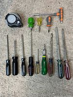 Full set image showing all 14 screwdrivers and 1 measuring tape arranged on carpet, displaying various handle styles, sizes, and colors.