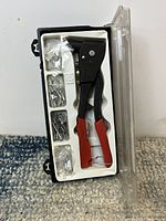 Top view of rivet tool in carrying case with compartments holding assorted rivets