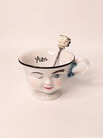 Front view of the winking Irish coffee cup showing face design and spoon inside, with 'Yum.' inscription inside the cup.